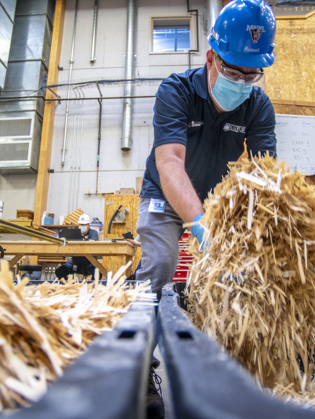A man in a hardhat holding wood strands used to make Oriented Strand Board (OSB)