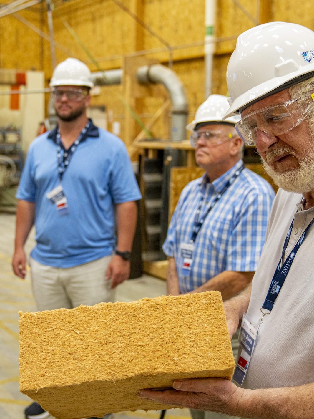 A man in a hard had holding a block of wood fiber insulation